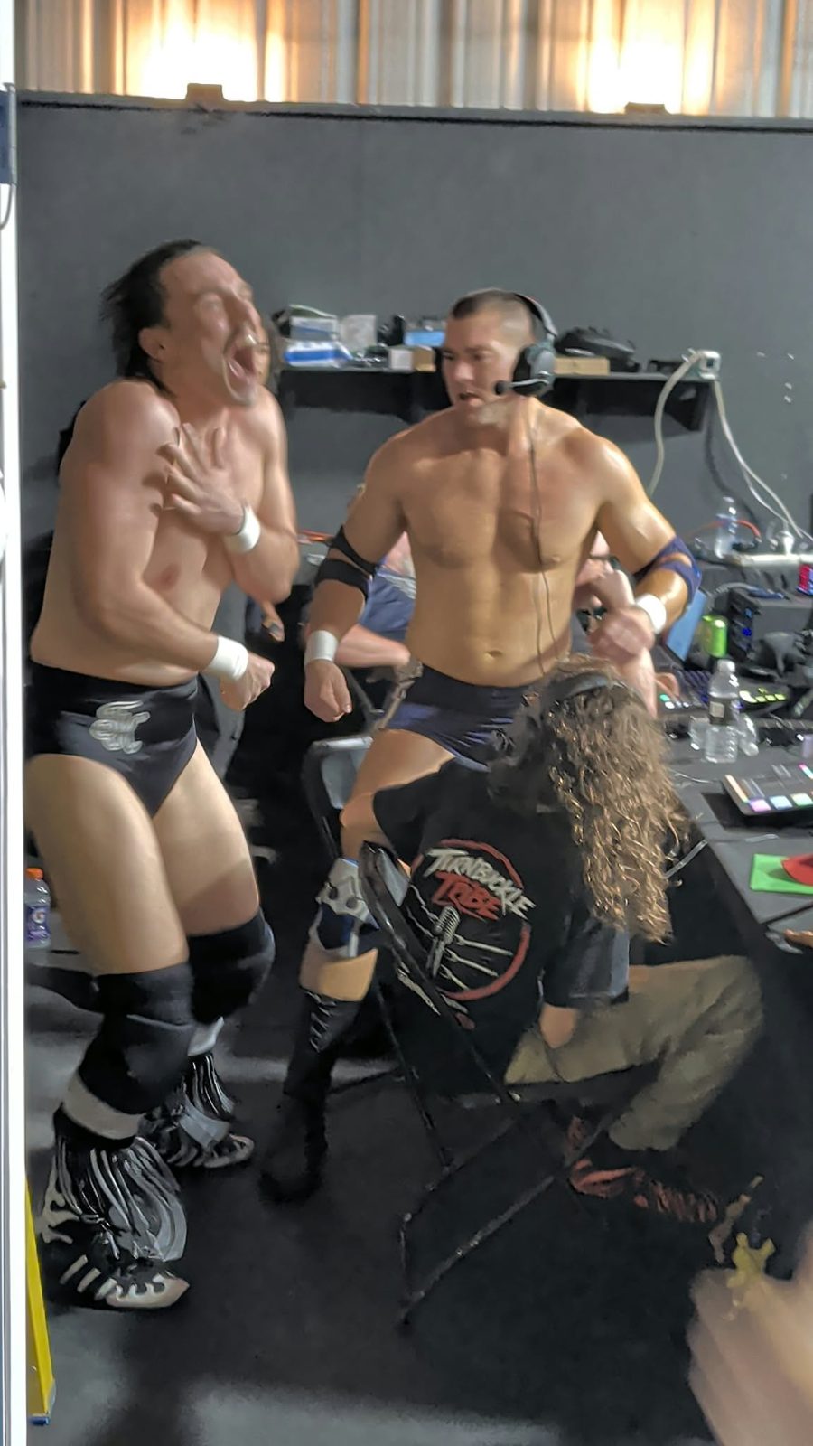Mathias wearing a headset at the CCP Podcasting commentary desk beside Trystan in his Turnbuckle Tribe shirt