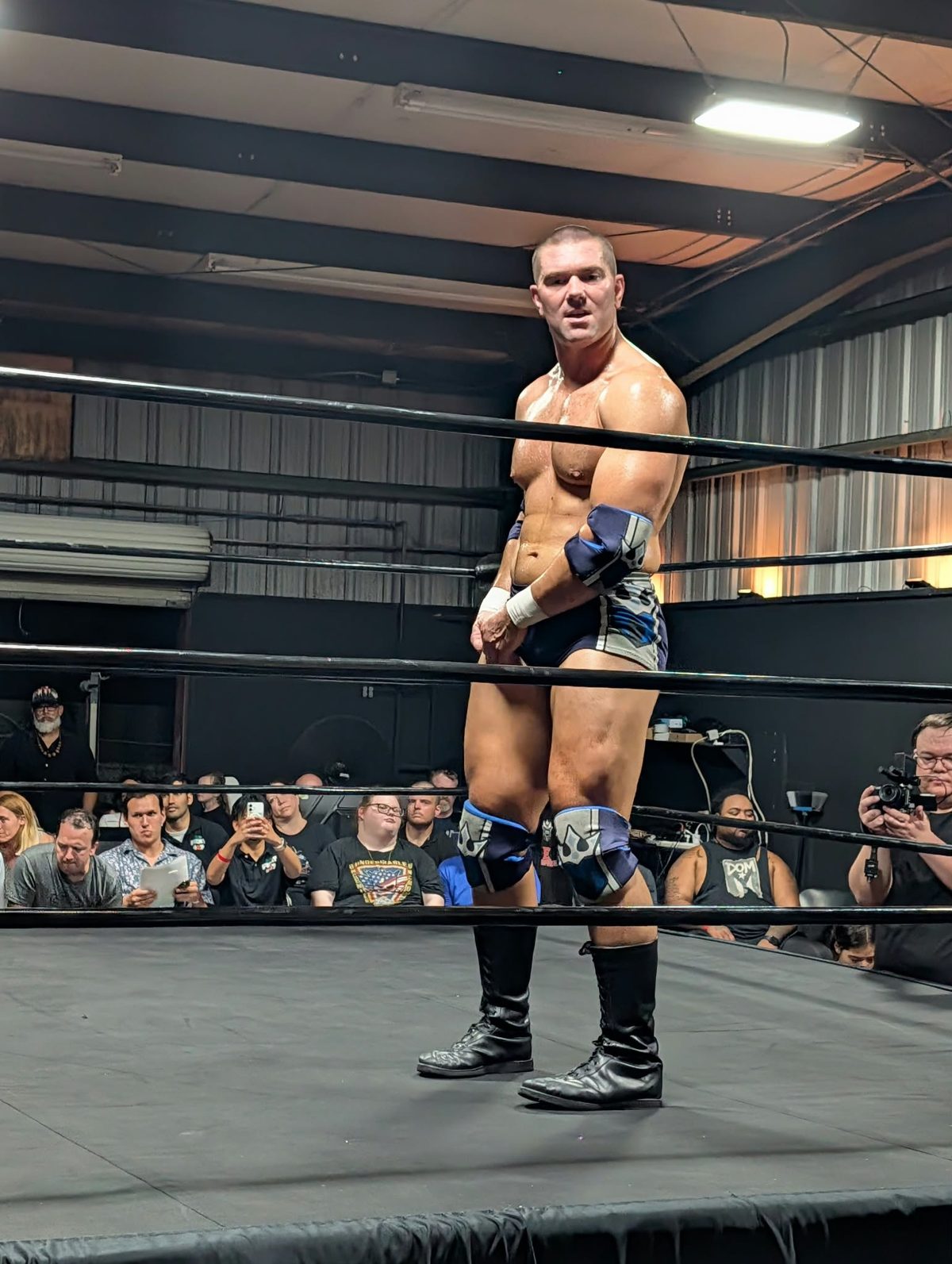 Mathias in navy and blue gear standing in the ring at CCP Podcasting in Casselberry, Florida, with fans ringside