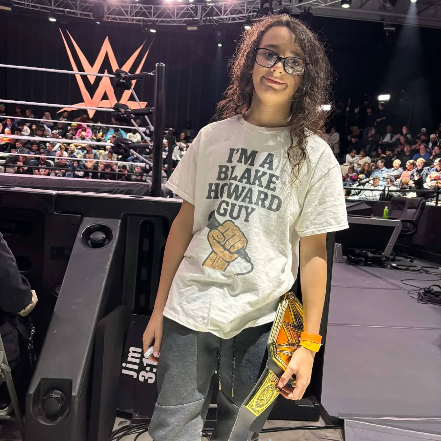Trystan ringside at a WWE event holding a championship belt