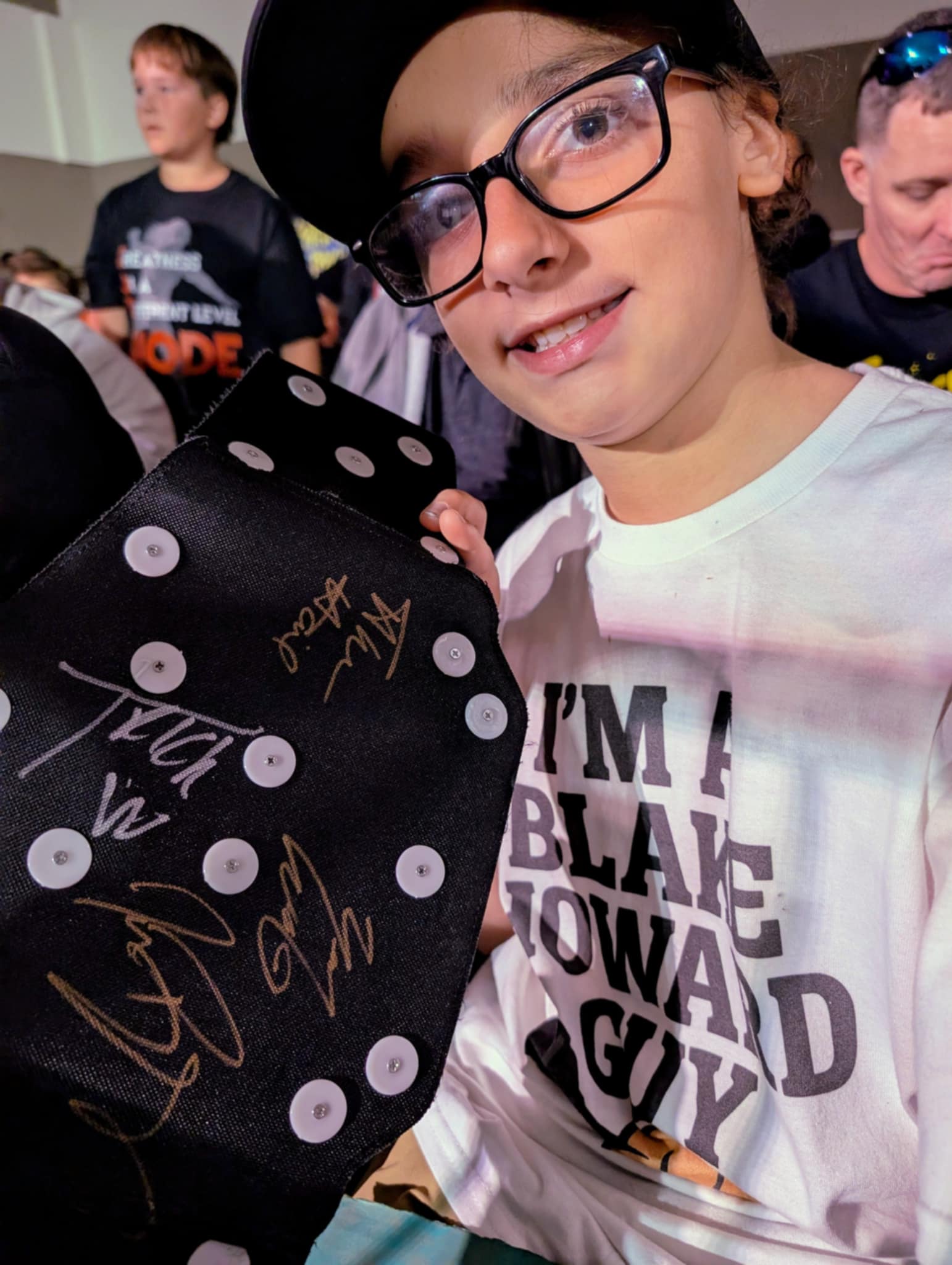Trystan proudly holding up his championship belt covered in autographs