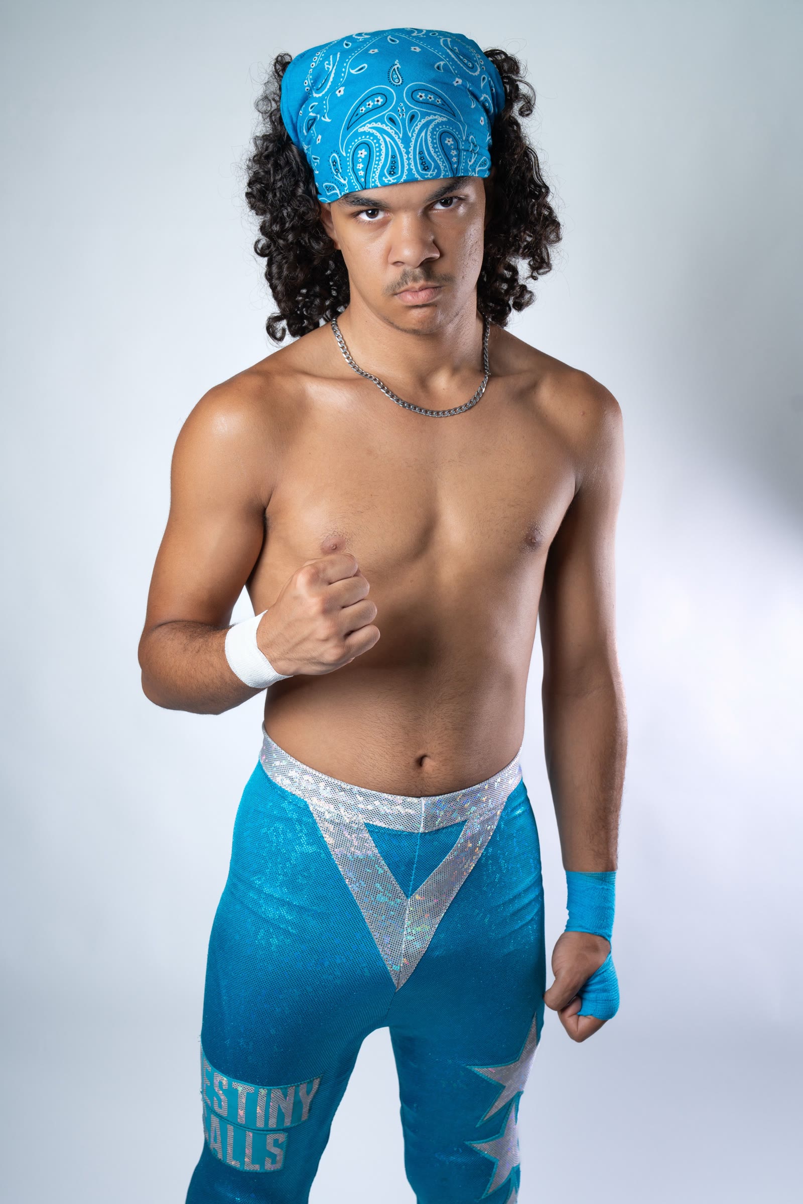 Destin professional wrestling headshot in a blue paisley bandana and blue trunks