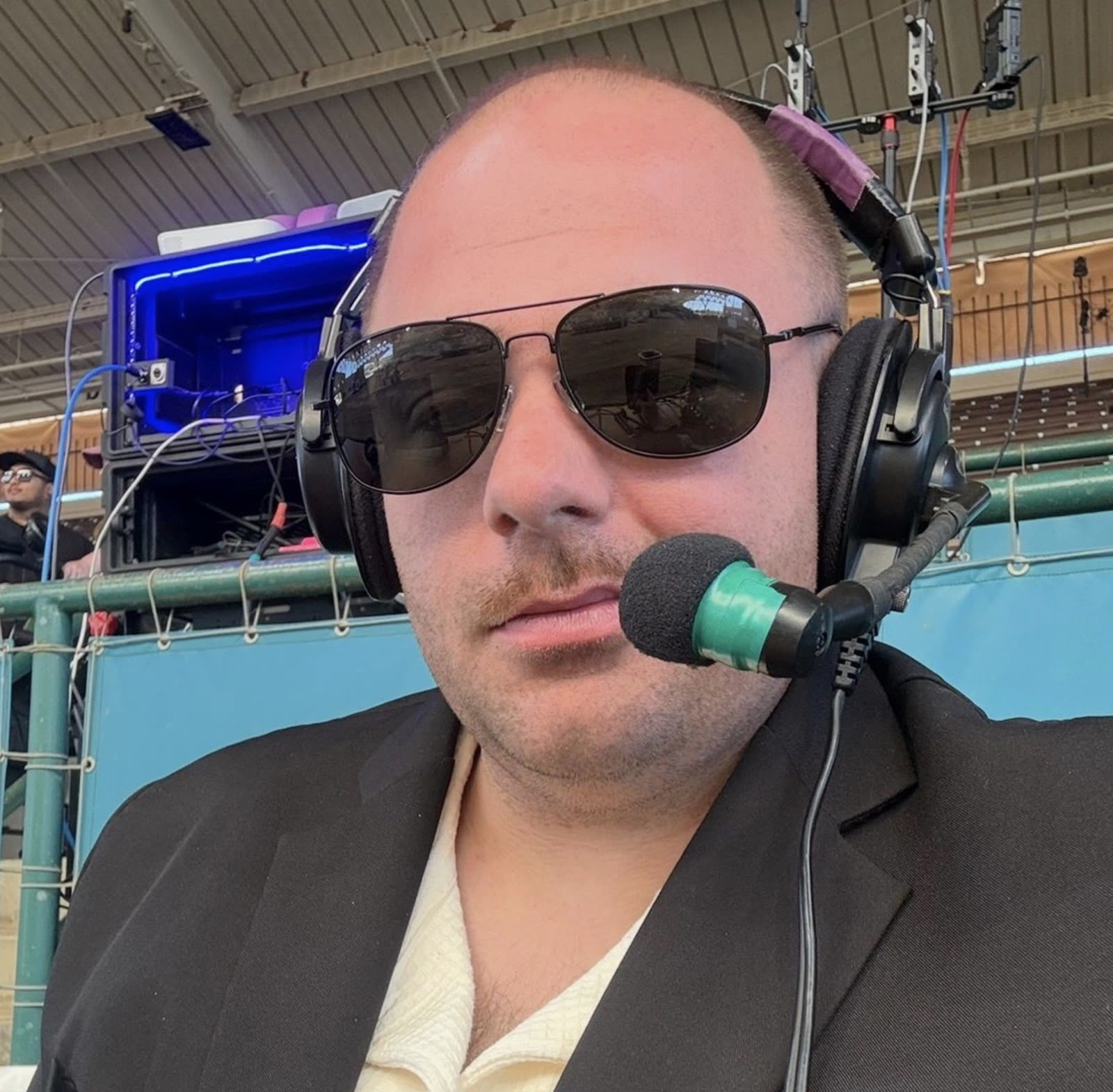 Kevin Cormac wearing a commentary headset and sunglasses at the broadcast table