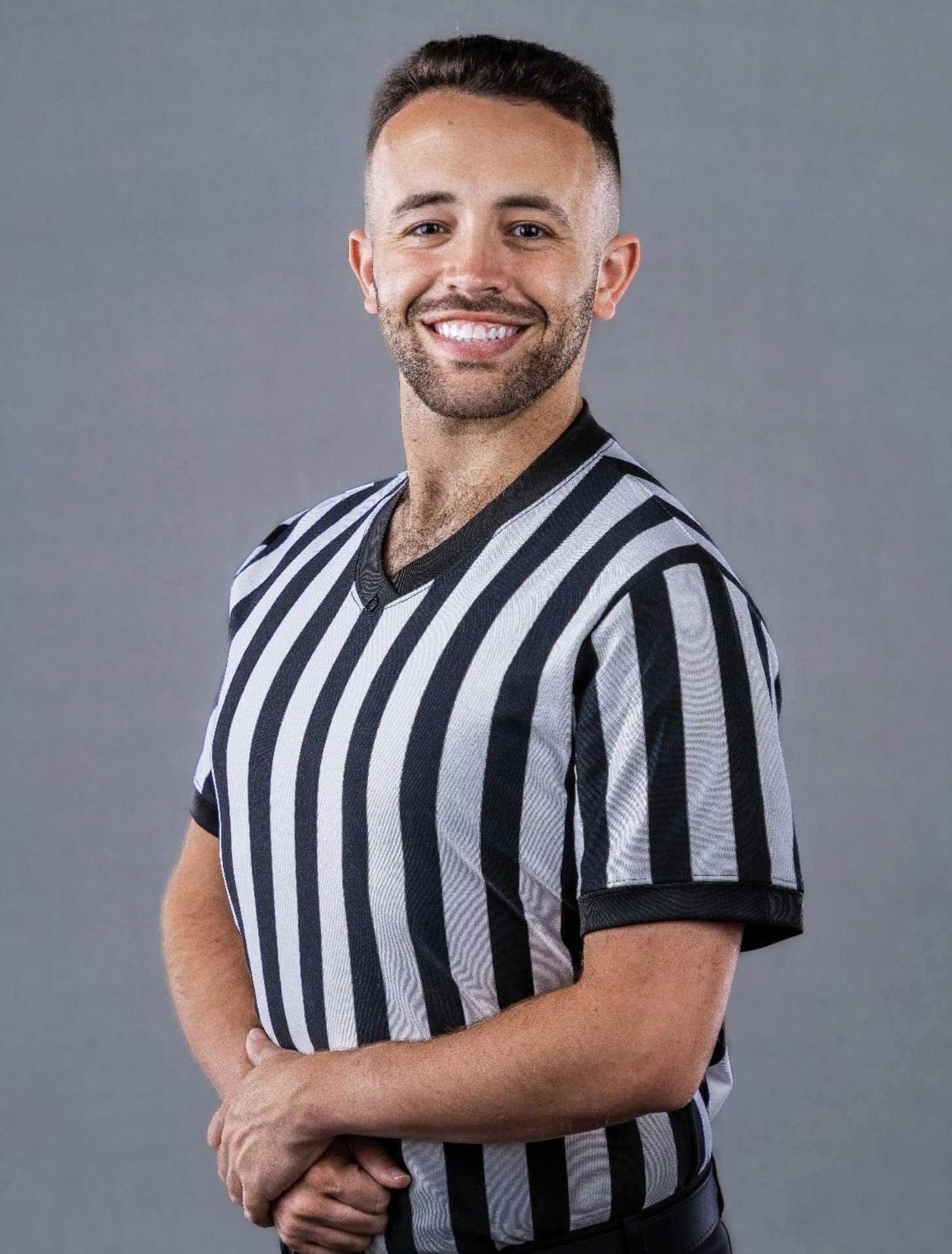 Referee David Sanderson smiling in his black-and-white striped referee shirt