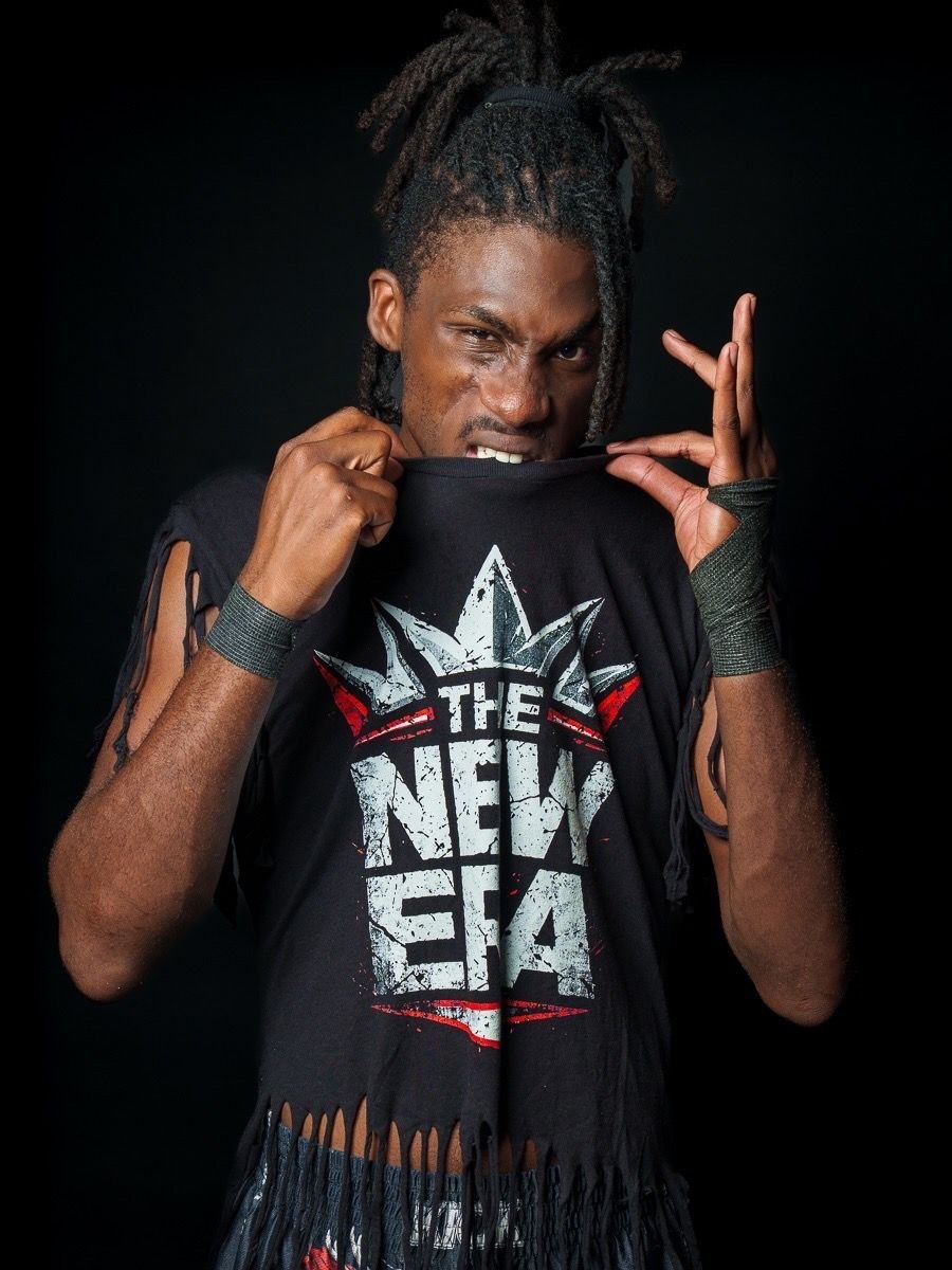 Gage Holloway biting the collar of his fringed The New Era shirt and throwing up a hand sign