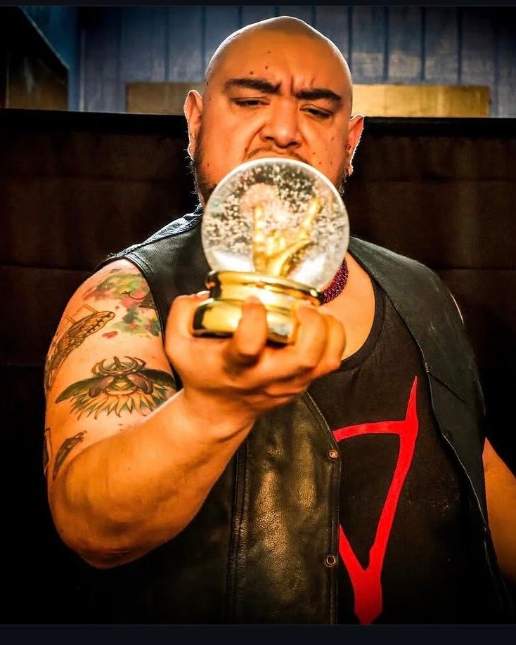Kaus holding a championship trophy in a wrestling setting